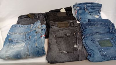 plusieurs paires de jeans pour homme posées sur une table blanche