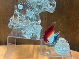 une sculpture en verre représentant un chien et un poisson, posée sur une table