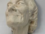 a sculpture of a woman ' s head on a white surface