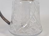 a glass pitcher with a silver lid on a white surface
