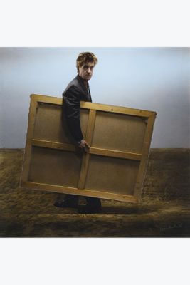 the man is holding a large piece of wood in his hands