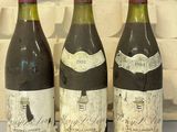 trois bouteilles de vin posées sur une table, à côté d'un clavier