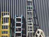 several ladders are lined up in front of a metal building