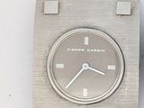 une montre argentée avec un bracelet noir posée sur une surface blanche