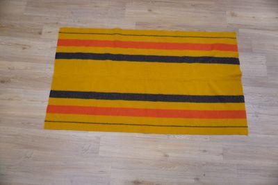un gros plan sur un tapis rayé jaune et noir posé sur un parquet