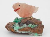 sculpture représentant un oiseau perché sur un rocher, posée sur une surface blanche