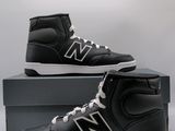 black and white new balance high top sneakers on display in front of a box
