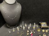 an assortment of silver and gold jewelry on display on a black background
