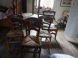 une table et six chaises dans une pièce où l'on aperçoit un lit à l'arrière-plan