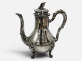 une théière ancienne en argent surmontée d'un oiseau