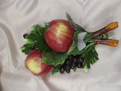 deux pommes sur une assiette, accompagnées de feuilles et de raisins