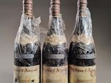 three bottles of wine wrapped in plastic sitting on top of a table
