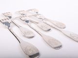 six spoons and a fork are sitting on a white surface