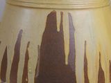 a yellow vase with brown spots on it sitting on a table