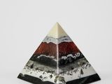 un gros plan d'un objet en forme de pyramide posé sur une surface blanche