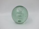 a green glass ball sitting on a white surface