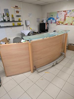 un comptoir d'accueil avec un plateau en verre, situé dans une petite pièce