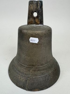 a metal bell with a sticker on it on a white surface