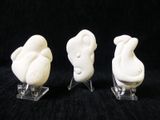three figurines of birds that are sitting on a stand