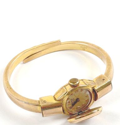 bracelet en or jaune avec une montre posée sur le côté, sur un fond blanc