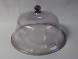 a glass clochet with a metal base on a white surface