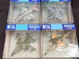 quatre maquettes d'avions en plastique sont rangées dans des boîtes posées sur une surface noire