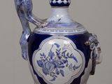 a blue and white vase on a table with a bird on it