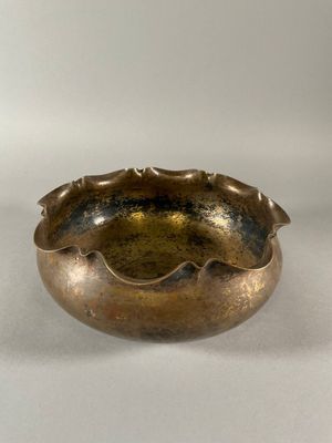 an old brass bowl sitting on top of a white surface