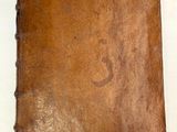 un vieux livre à la couverture marron posé sur une table blanche