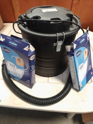 une photo d'un seau noir avec un tuyau d'arrosage et deux paquets de papier toilette