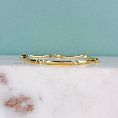 bracelet rigide plaqué or, orné de diamants, posé sur une dalle de marbre