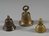 three brass bells sitting next to each other on a white surface