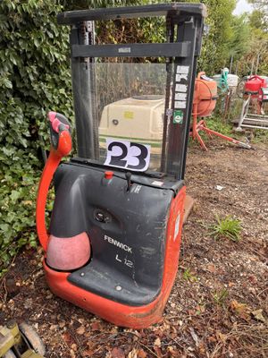 an orange and black forklift sitting in the middle of a yard