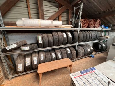 de nombreux pneus empilés sur les étagères du garage