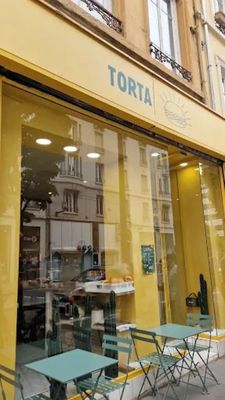 des tables et des chaises disposées à l'extérieur d'un magasin, sur le trottoir