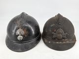 pair of antique german fire helmets, one with a helmet and the other with a helmet with a flower on it