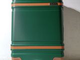 a green suitcase sitting on wheels against a white wall