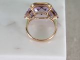 a close up of a gold ring with three purple stones on a marble surface