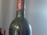 a man holding a bottle of wine next to two bottles of wine