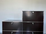 deux commodes noires avec des poignées chromées dans une pièce