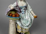 a figurine of a woman holding a basket of apples