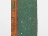 un vieux livre à la couverture verte posé sur une surface blanche