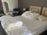 a bed with a white comforter and pillows in a room
