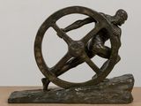 statue of a man holding a wheel on a wooden base
