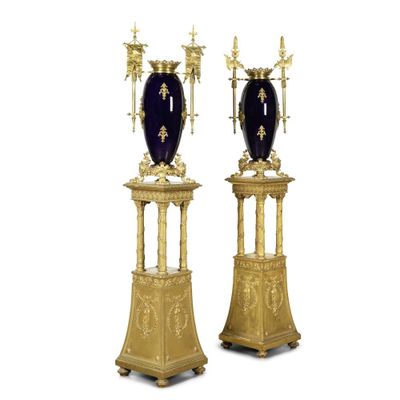 une paire de vases dorés et bleus sur des socles, sur fond blanc