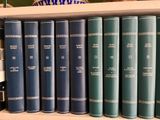 many books on a book shelf with a blue vase
