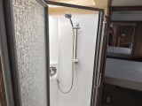 a bathroom with a shower and a bed in the background