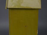 an old yellow birdhouse sitting on top of a gray surface