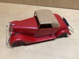 une petite voiture rouge avec un toit beige posée sur une table