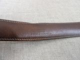brown leather belt with white stitching on it sitting on a couch